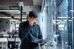 Uomo preoccupato davanti al laptop: errori digitali e problemi da evitare online con concorsi a premio