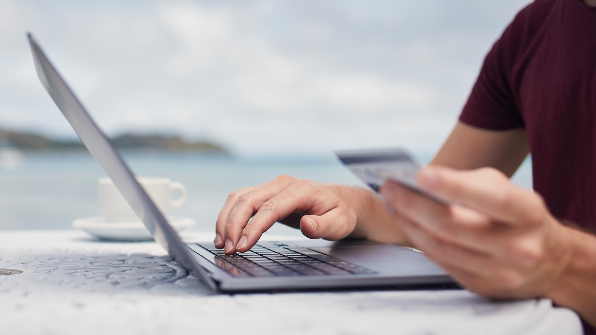 Persona che utilizza un laptop mentre tiene una carta di credito per un acquisto online.