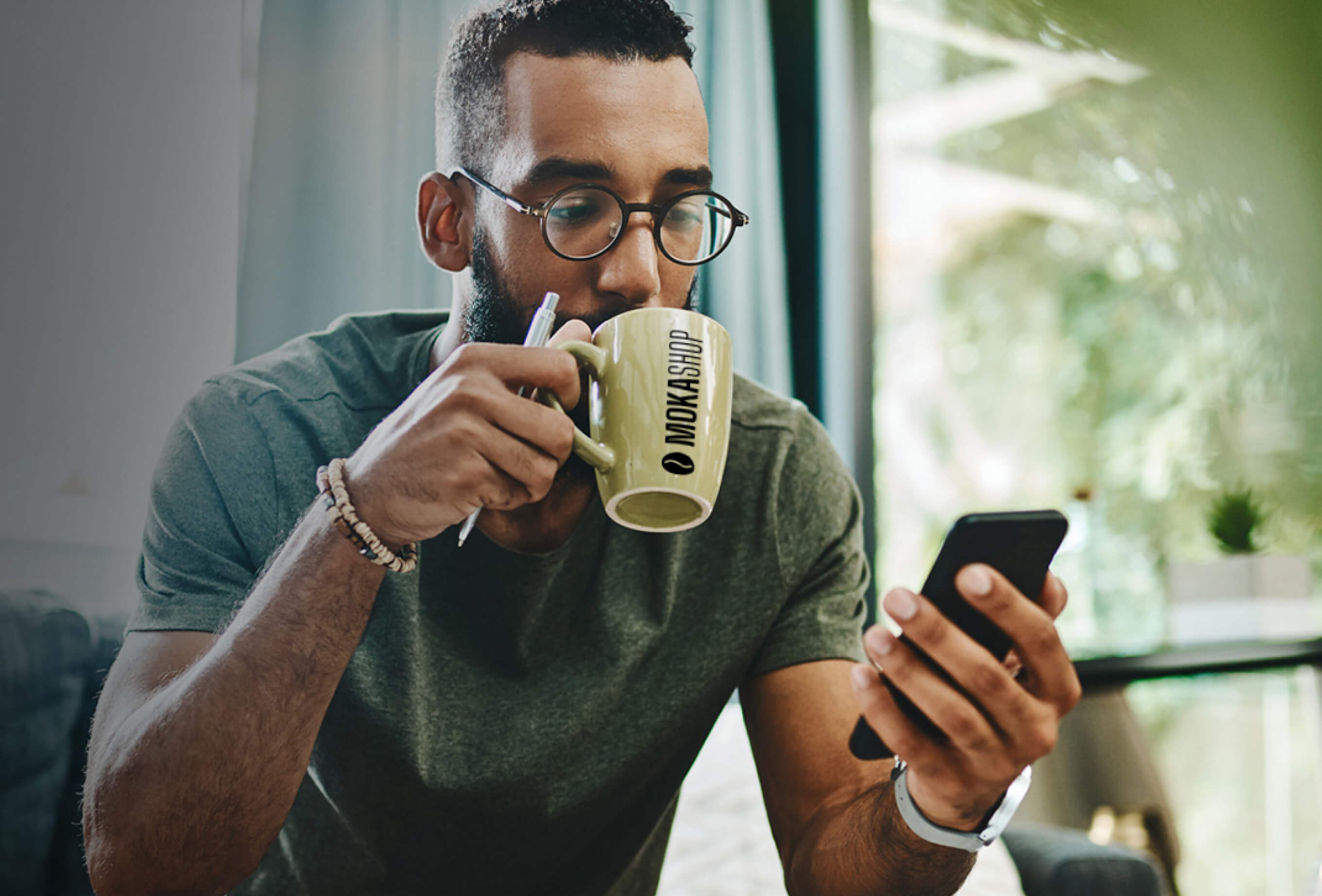 Uomo che sorseggia un caffé in una tazzina con la scritta MokaShop.